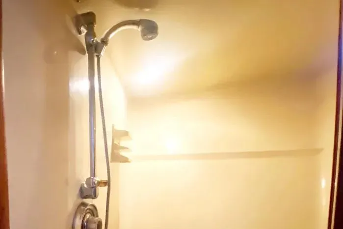 Slide: The Image of Shower area inside a 1990 Viking Motor Yacht, featuring a chrome showerhead and beige walls. - 42