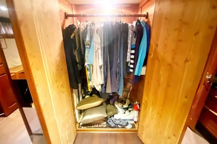 Slide: The Image of Closet inside 1990 Viking Motor Yacht with clothes and accessories neatly arranged. - 49