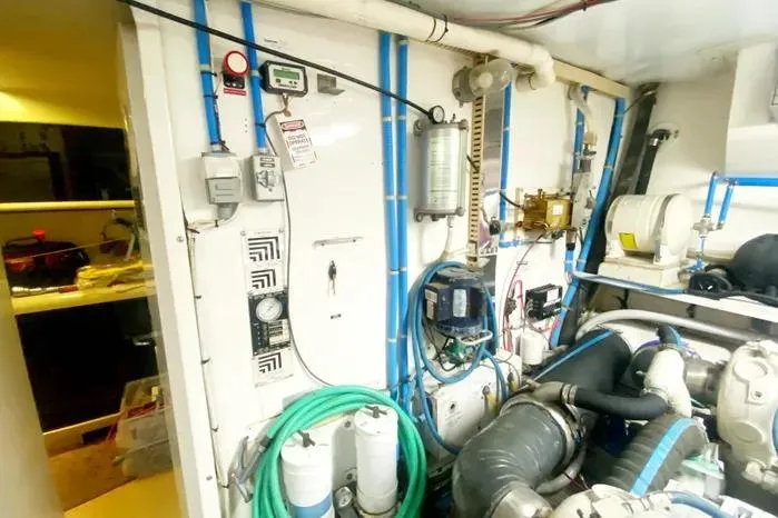 Slide: The Image of Engine room of a 1990 Viking Motor Yacht with various equipment and hoses. - 62