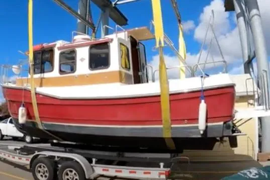 Slide: The Image of 2010 Ranger Tugs R-25 SC boat on trailer, red and white, in a marina setting. - 2