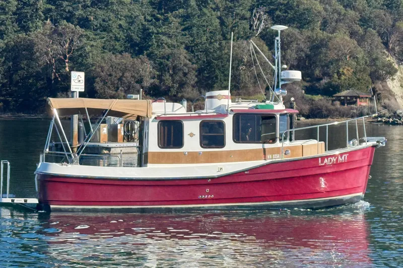 Slide: The Image of 2010 Ranger Tugs R-25 SC boat on calm water, surrounded by lush greenery. - 4