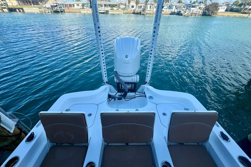 Slide: The Image of 2024 Sea Hunt BX 25 FS boat with seating and motor, docked on calm water. - 13