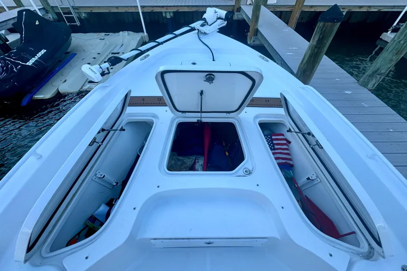 Slide: The Image of 2024 Sea Hunt BX 25 FS boat storage compartments with American flag and gear. - 16