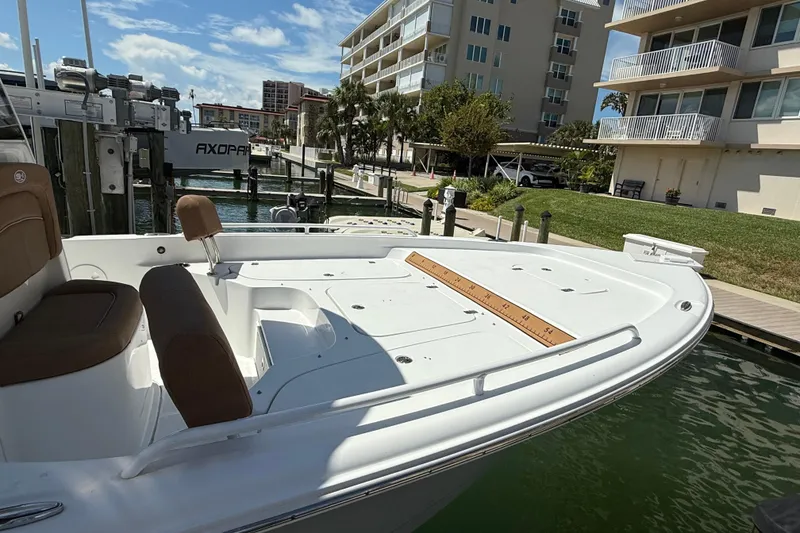Slide: The Image of 2024 Sea Hunt BX 25 FS boat docked near waterfront buildings under a clear sky. - 22