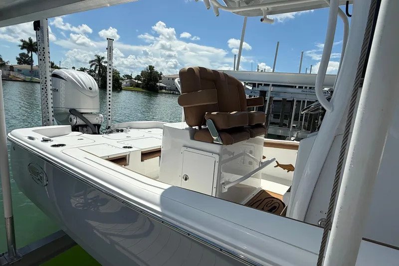 Slide: The Image of 2024 Sea Hunt BX 25 FS boat interior with seating and motor, docked by the water. - 23