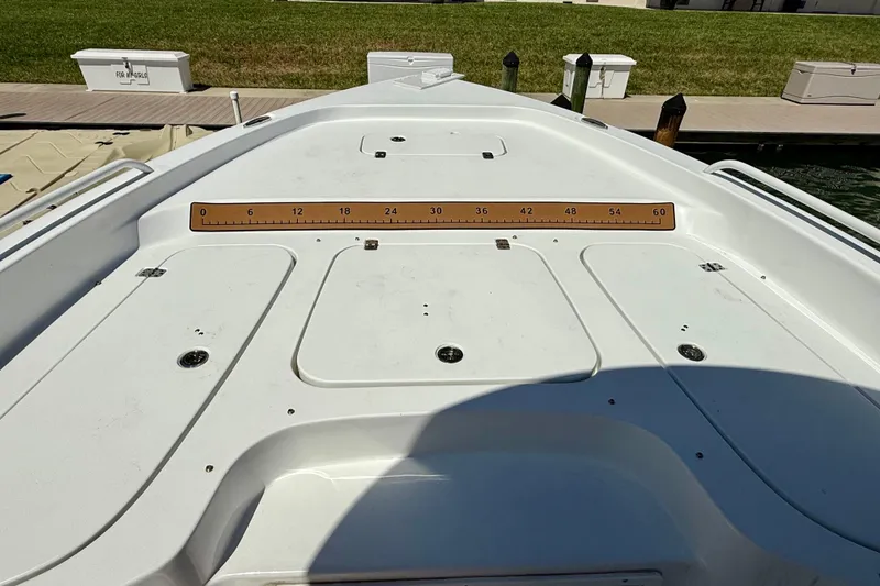 Slide: The Image of 2024 Sea Hunt BX 25 FS boat deck with measurement ruler, docked by grassy area. - 7