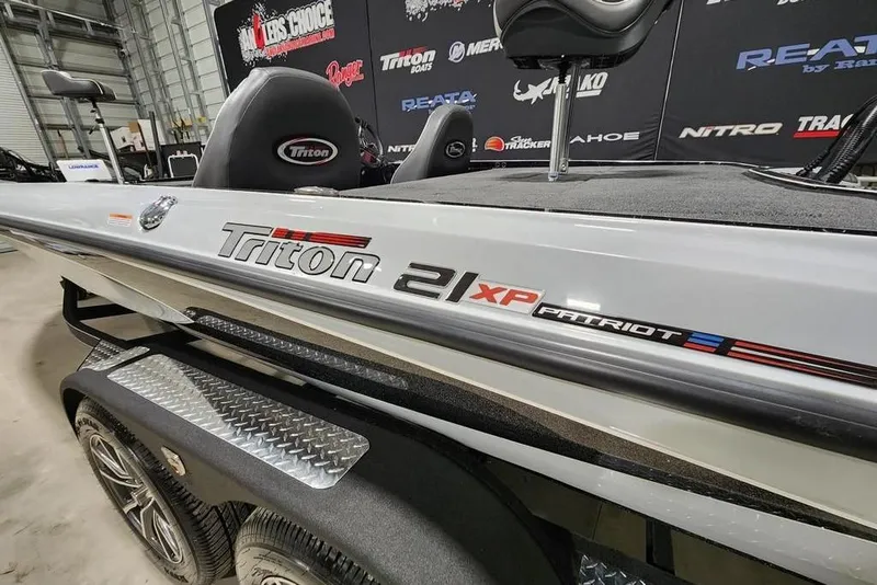 Slide: The Image of 2026 Triton 21XP Patriot boat displayed indoors, showcasing sleek design and branding. - 12