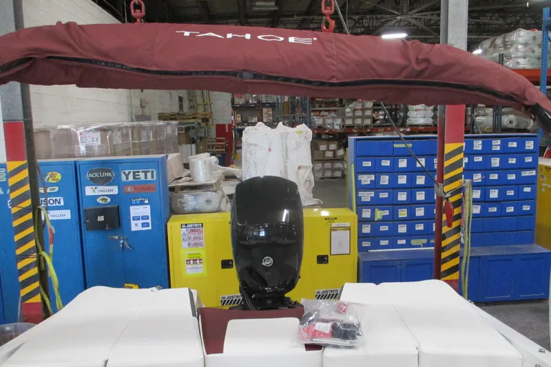 Slide: The Image of 2024 Tahoe 200 S boat in warehouse, featuring red canopy and motor. - 14
