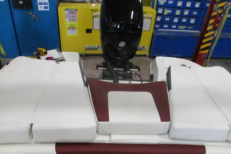 Slide: The Image of 2024 Tahoe 200 S boat interior with cushioned seating and outboard motor in workshop. - 16