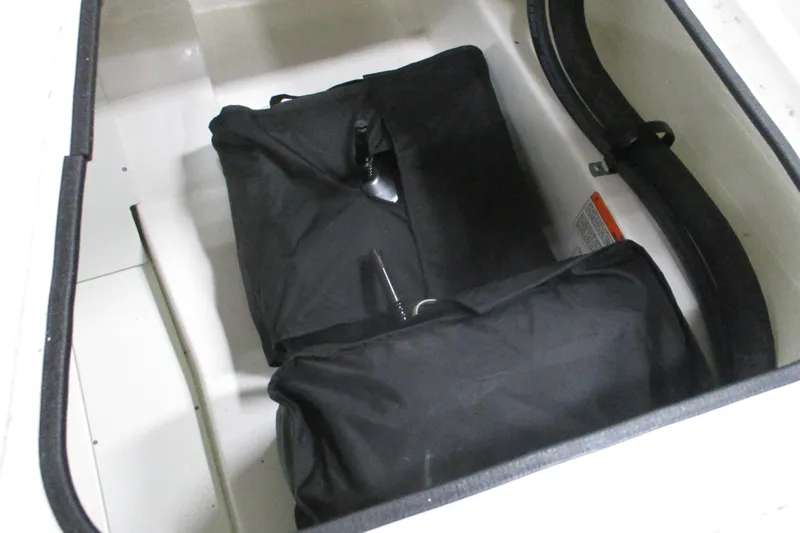 Slide: The Image of Storage compartment in 2024 Tahoe 200 S boat with black bags inside. - 18