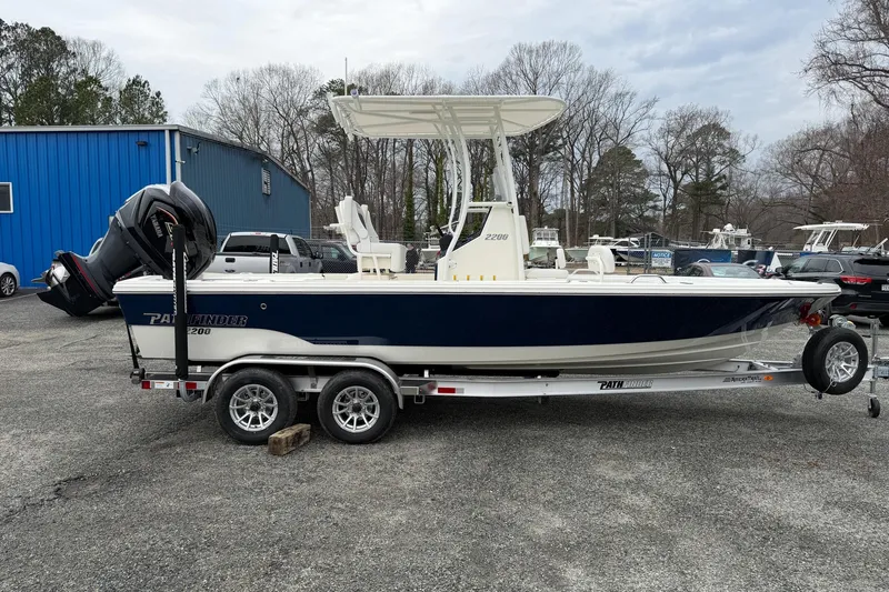Slide: The Image of 2026 Pathfinder 2200 TRS boat on trailer, parked outdoors near blue building. - 11