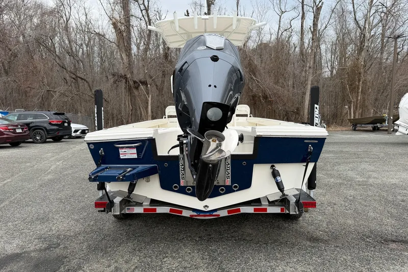 Slide: The Image of 2026 Pathfinder 2200 TRS boat with outboard motor, parked in a wooded area. - 14