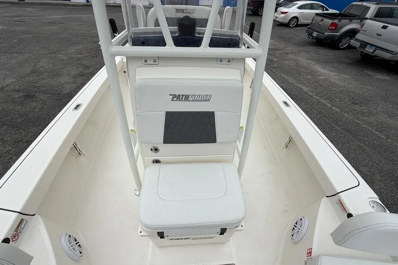 Slide: The Image of 2026 Pathfinder 2200 TRS boat interior with seating and console, parked in a lot. - 25