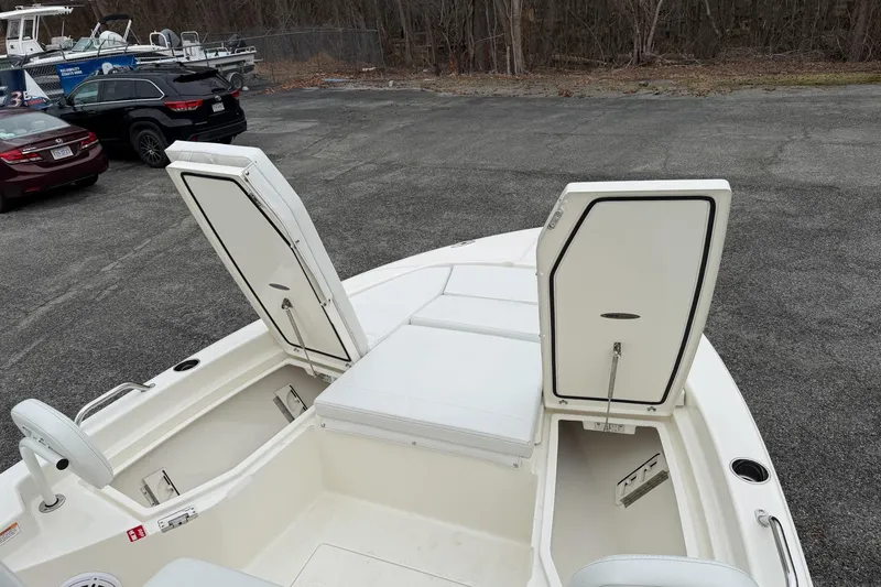 Slide: The Image of 2026 Pathfinder 2200 TRS boat with open storage compartments, parked on asphalt. - 26
