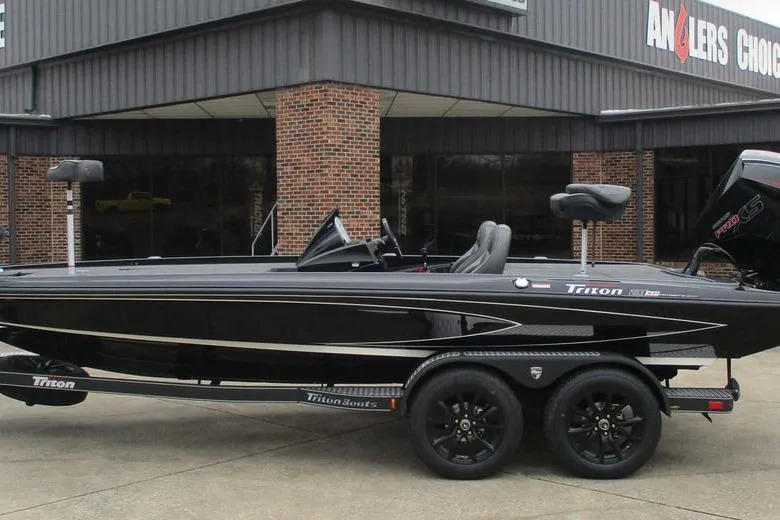 Slide: The Image of 2026 Triton 21XP Patriot boat on trailer outside Anglers Choice building. - 1