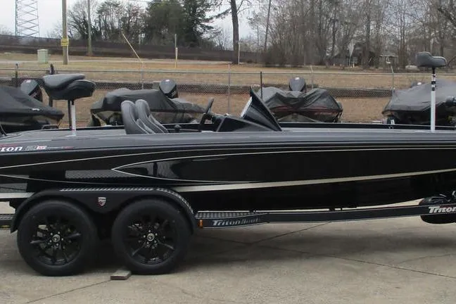 Slide: The Image of 2026 Triton 21XP Patriot boat on trailer, sleek black design, parked outdoors. - 7