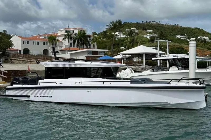 The Image of 2025 Axopar 37 XC Cross Cabin boat docked in a scenic marina setting. - 0
