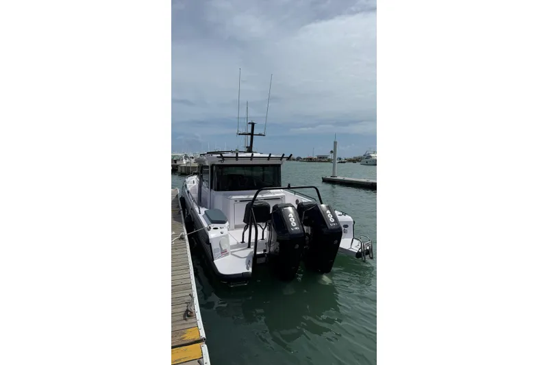 Slide: The Image of 2025 Axopar 37 XC Cross Cabin boat docked with dual outboard engines. - 7