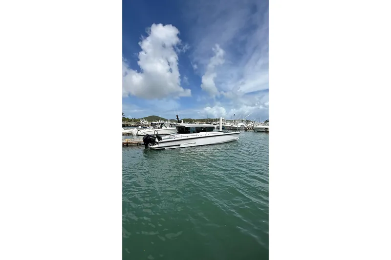 Slide: The Image of 2025 Axopar 37 XC Cross Cabin boat docked in a marina under a blue sky. - 8