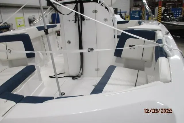 Slide: The Image of 2024 Tahoe 2150 CC boat interior with blue and white seating in a showroom. - 2