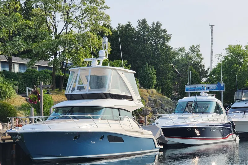 Slide: The Image of 2020 Tiara Yachts F44 Flybridge docked beside another boat, surrounded by lush greenery. - 10