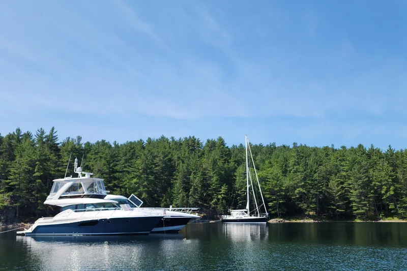Slide: The Image of 2020 Tiara Yachts F44 Flybridge on serene lake with forest backdrop. - 13