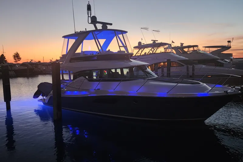 Slide: The Image of 2020 Tiara Yachts F44 Flybridge at sunset, illuminated with blue lights. - 7