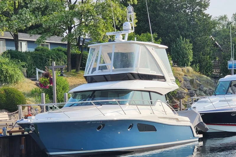 Slide: The Image of 2020 Tiara Yachts F44 Flybridge docked, surrounded by lush greenery and calm waters. - 9