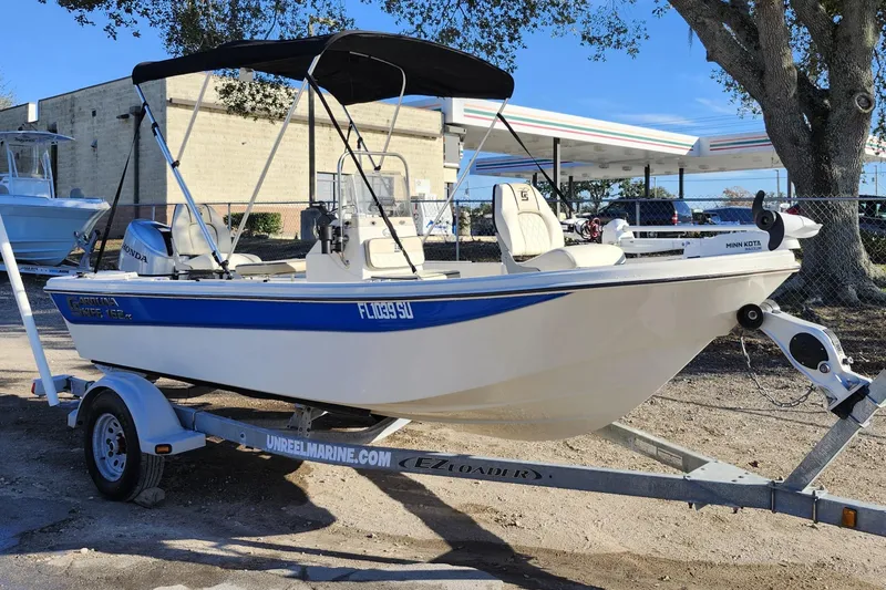Slide: The Image of 2020 Carolina Skiff 162 JLS boat on trailer, parked outdoors under a tree. - 3