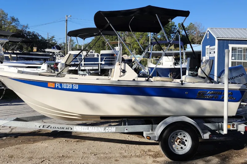 Slide: The Image of 2020 Carolina Skiff 162 JLS boat on trailer, parked outdoors with blue canopy. - 4