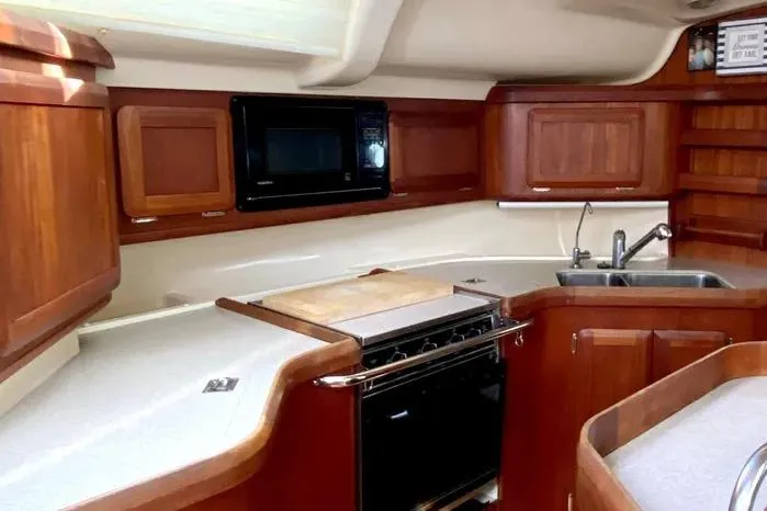Slide: The Image of 1997 Hunter 430 yacht kitchen with wooden cabinets, stove, microwave, and sink. - 10