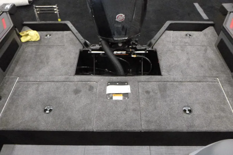 Slide: The Image of 2025 Alumacraft Trophy 185X Sport boat interior with carpeted deck and motor. - 13