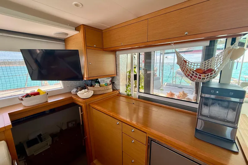 Slide: The Image of Interior of 2016 Lagoon 450 F yacht with wooden cabinetry, TV, and fruit hammock. - 27