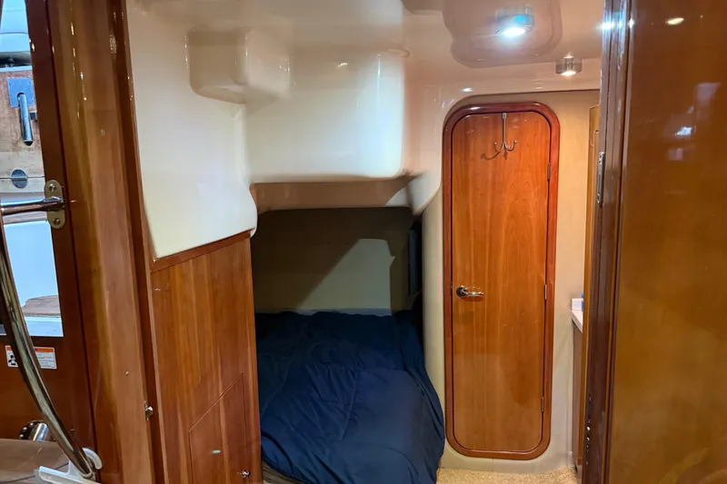 Slide: The Image of 2012 Regal 46 Sport Coupe cabin interior with wooden door and cozy sleeping area. - 19