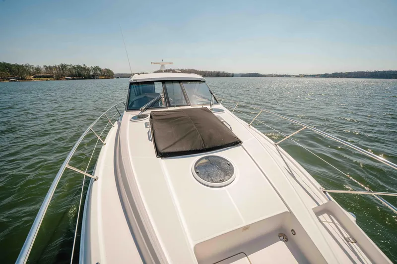 Slide: The Image of 2012 Regal 46 Sport Coupe cruising on a serene lake under clear skies. - 47