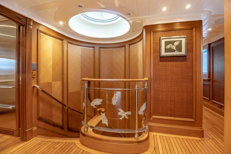 Slide: The Image of Luxurious yacht interior with wooden paneling, glass railing, and framed bird artwork. - 36