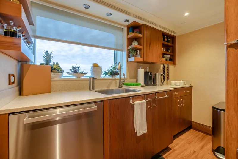 Slide: The Image of Modern yacht kitchen with wooden cabinets, stainless steel appliances, and decorative plants by the window. - 38