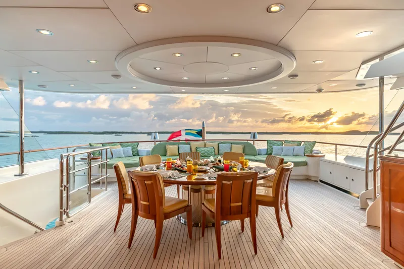 Slide: The Image of Luxurious yacht deck with dining setup, sunset view, and ocean backdrop, Burger Custom 2010 model. - 46