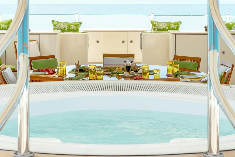 Slide: The Image of Luxurious yacht deck with jacuzzi and elegant dining setup, featuring green and yellow accents. - 56