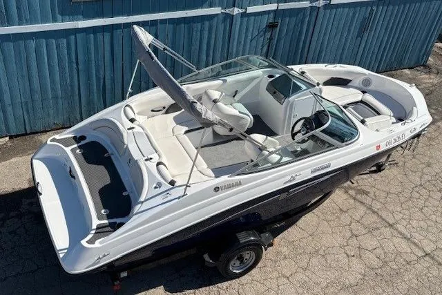 Slide: The Image of 2012 Yamaha Boats SX190, white and black, parked on a trailer near a blue fence. - 5