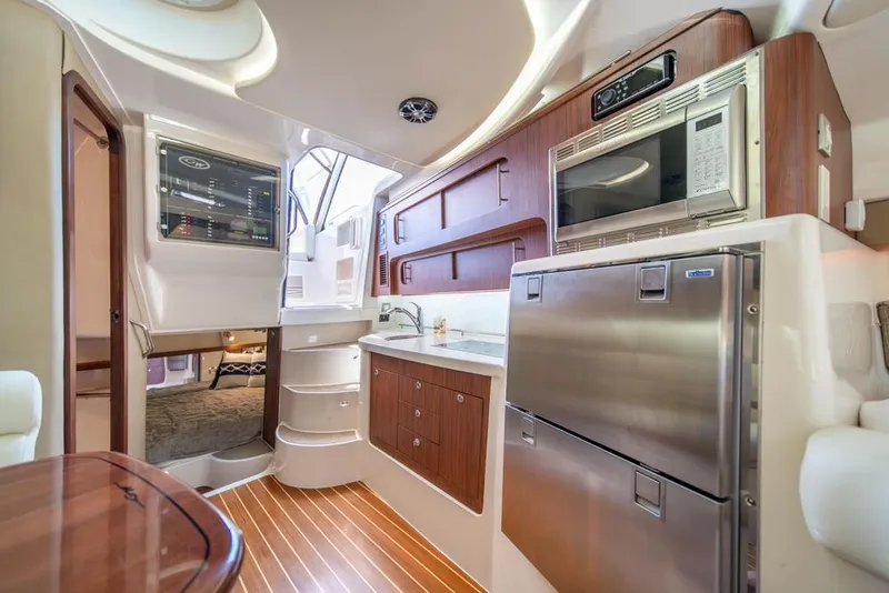 Slide: The Image of 2019 Grady-White Express boat interior with modern kitchen and wood accents. - 20