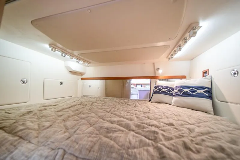 Slide: The Image of 2019 Grady-White Express cabin interior with cozy bedding and ambient lighting. - 22