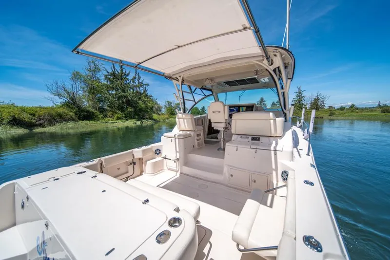 Slide: The Image of 2019 Grady-White Express boat on serene water, featuring spacious deck and canopy. - 27