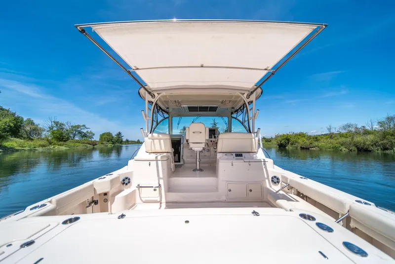 Slide: The Image of 2019 Grady-White Express boat on serene waterway under clear blue sky. - 28