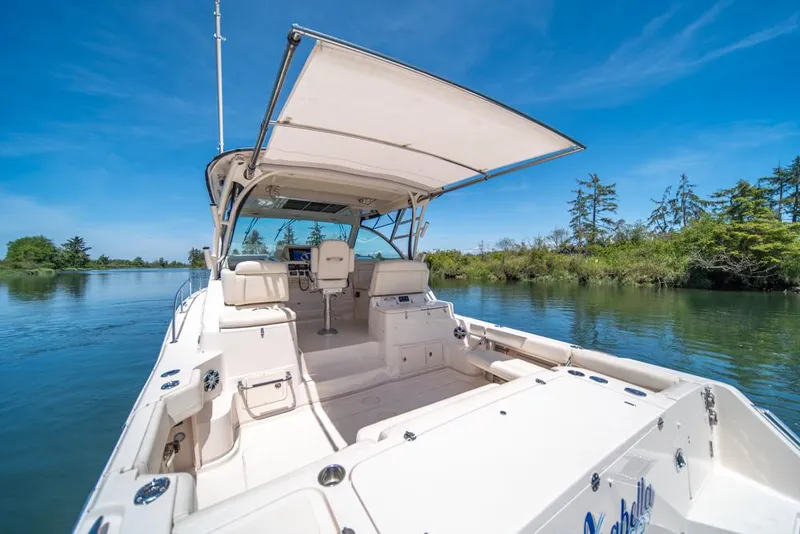 Slide: The Image of 2019 Grady-White Express boat on serene water, clear sky, lush greenery. - 29