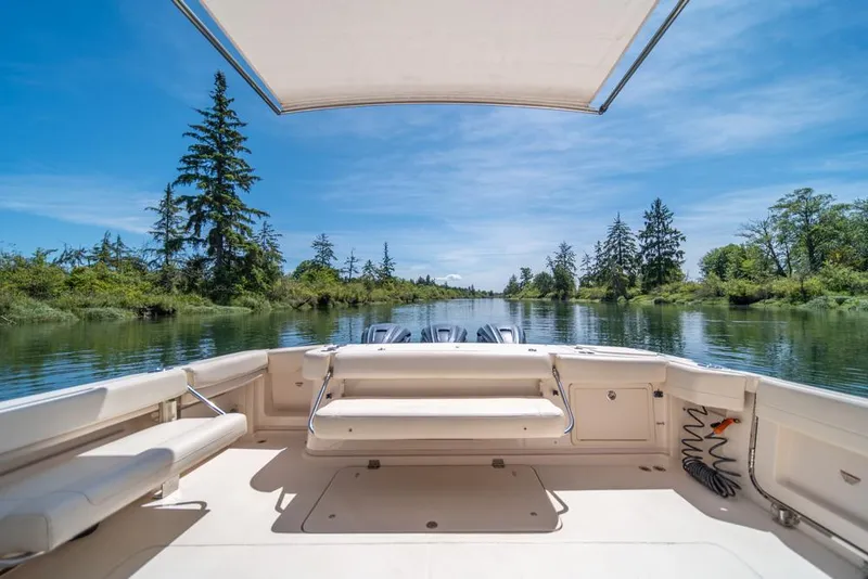 Slide: The Image of 2019 Grady-White Express boat on serene river with lush greenery and clear blue sky. - 32