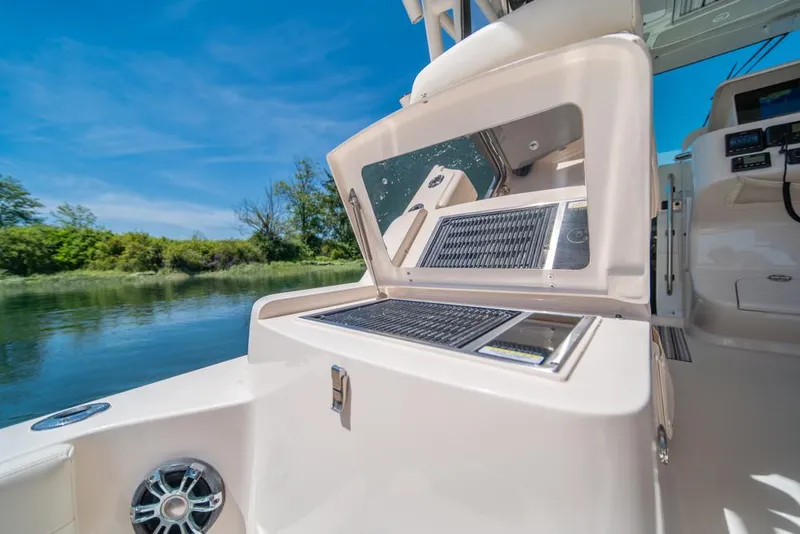 Slide: The Image of 2019 Grady-White Express boat interior with open storage compartment, near calm water. - 47