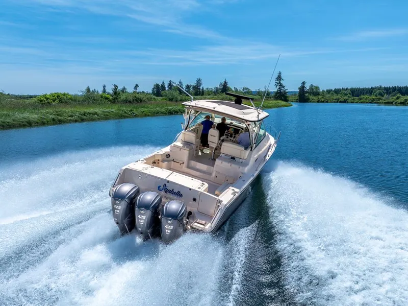 Slide: The Image of 2019 Grady-White Express boat cruising on a scenic river with triple outboard engines. - 8