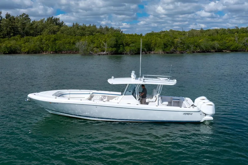 Slide: The Image of 2017 Intrepid 375 Center Console boat on calm water, surrounded by lush greenery. - 22