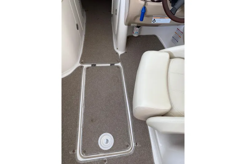 Slide: The Image of Interior view of 2005 Chaparral Sunesta 236 boat, featuring beige carpet and white seating. - 11